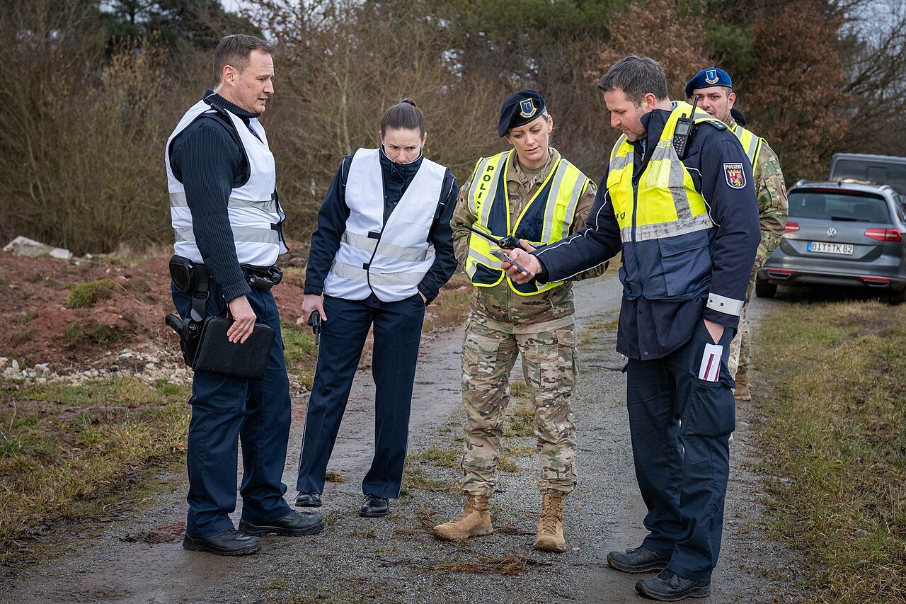 Police officers and a soldier reviewing a handheld drone-detection device during a counter-UAS airspace-security exercise